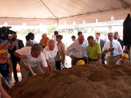 The speakers dig with their ceremonial shovels while WHAS&#039;s Joe Arnold looks on.
