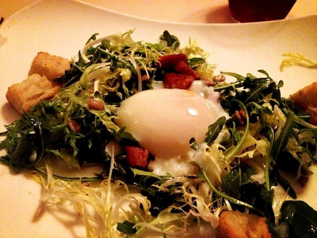 Arugula and Frisee Salad topped with Bacon Lardons, Toasted Sunflower Seeds and Croutons with a Lemon-Cracked Pepper Vinaigrette Topped with Poached Egg