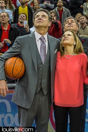 Rick and Joanne Pitino watch the video board tribute to the coaches 300th victory as the Cardinal coach. Athletic director Tom Jurich looks on.