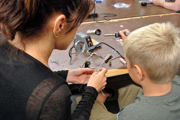 Shannon Runke holds the wires as son Walter Ray solders them, attaching them to board